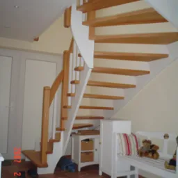 Jasne, drewniane schody z białymi elementami konstrukcyjnymi, widoczne z boku, z półką pod spodem i dziecięcą ławeczką z misiami obok.